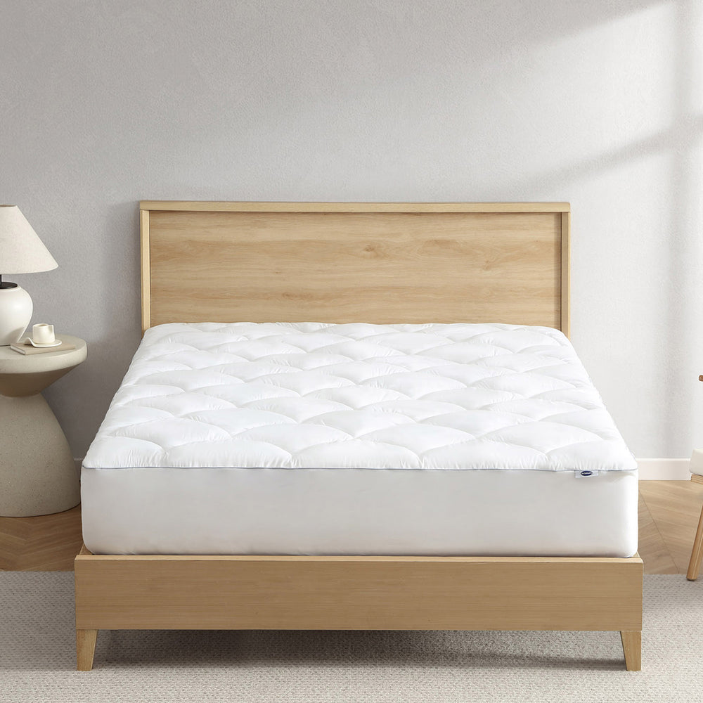 Dr. Scholl's™ CloudEase™ Mattress Pad displayed on a bed with a light wood frame